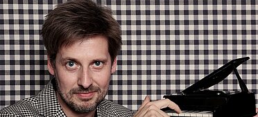 Daniel Helfrich mit Klavier in der Hand.