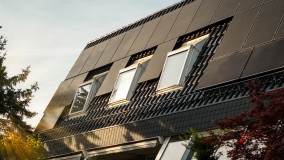 Dach mit Solaranlagen und Fenstern. Wird von der Sonne angestrahlt.