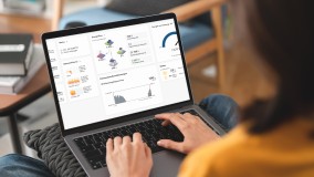 Eine Person hat einen Laptop auf dem Schoß. Der Bildschirm zeigt das Dashboard des Sunny Home Managers mit bspw. dem aktuellen Energieverbrauch des Hauses und der Solarstromproduktion.