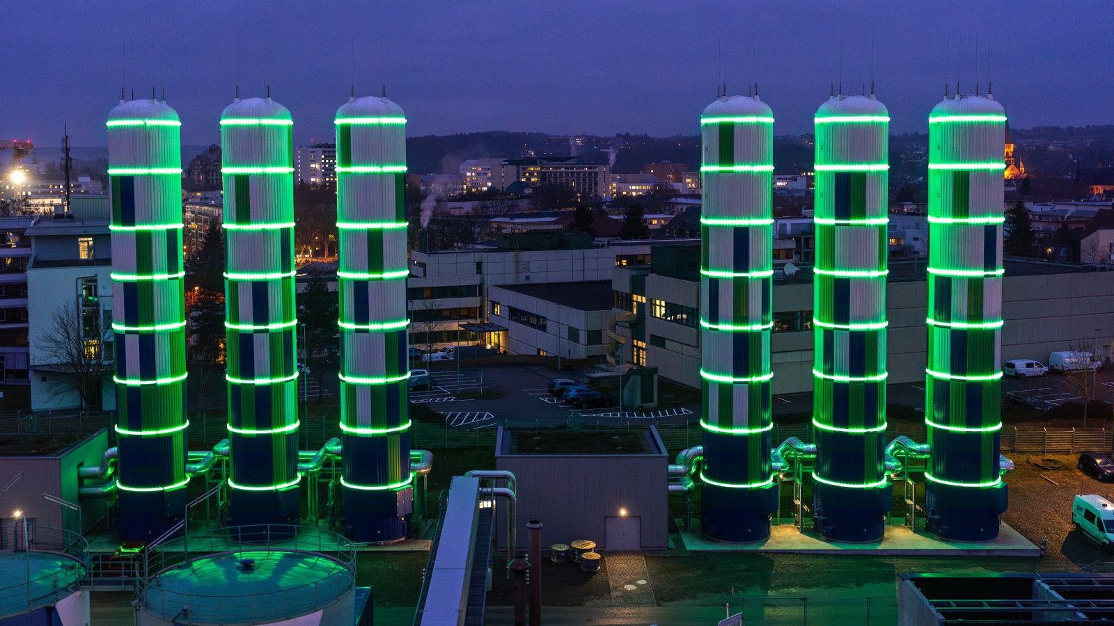 Nachthimmel über Stadtwerke Kaiserslautern Heizkraftwerk mit leuchtend grün leuchtenden Wärmespeichern.