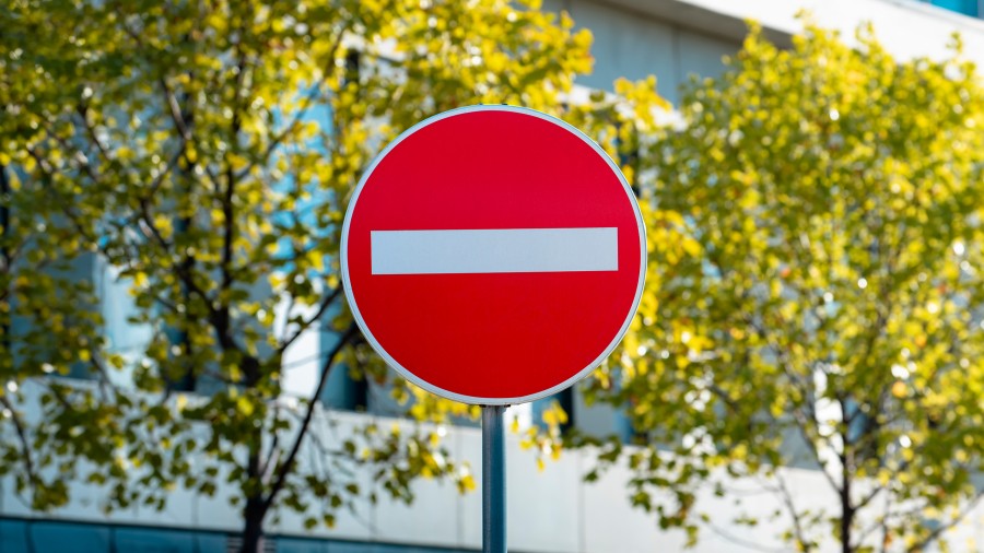 Baustellenschild mit Arbeiten-Symbol vor grünem Stadtpark und Brücke in Kaiserslautern, Verkehrshinweis Straße.