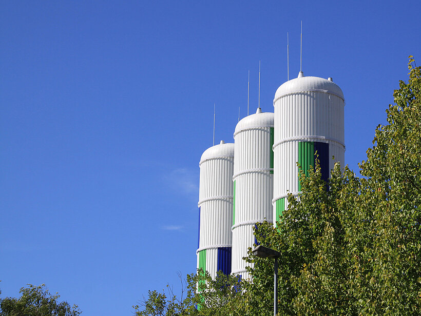 Blick auf Wärmespeicher und Bäume mit blauem Himmel