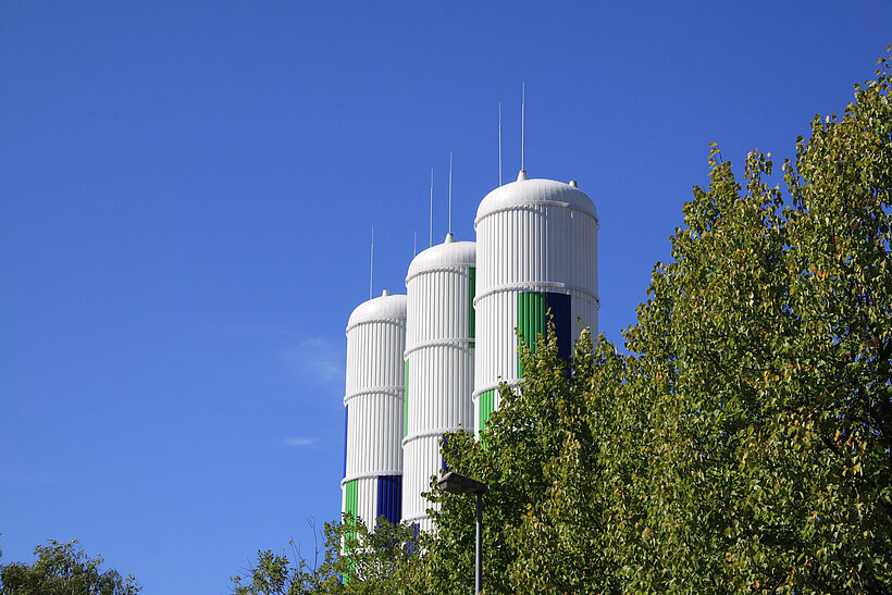 Blick auf Wärmespeicher und Bäume mit blauem Himmel