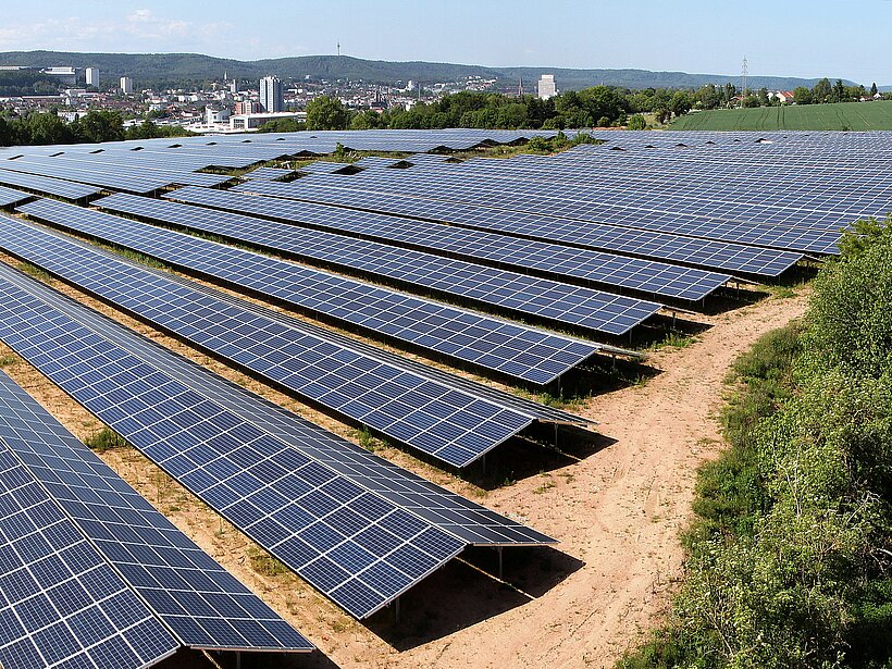 Luftaufnahme auf eine Photovoltaik-Anlage auf einer Fläche abseits der Stadt