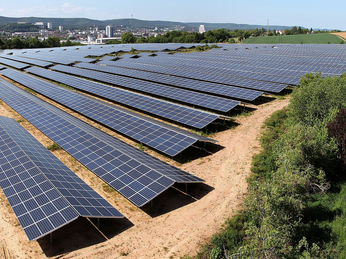 Luftaufnahme auf eine Photovoltaik-Anlage auf einer Fläche abseits der Stadt