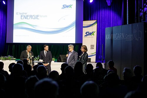 Personen sprechen auf Bühne Energieforum vor Publikum