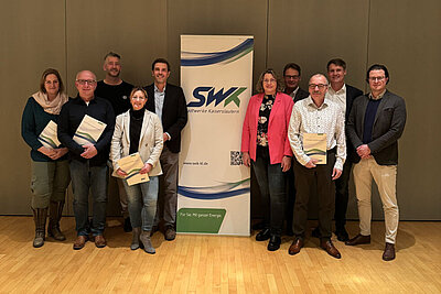 Personen in SWK-Gebäude stehen rechts und links von einem SWK-Rollup bei einer Energiewende-Vertragsunterzeichnung