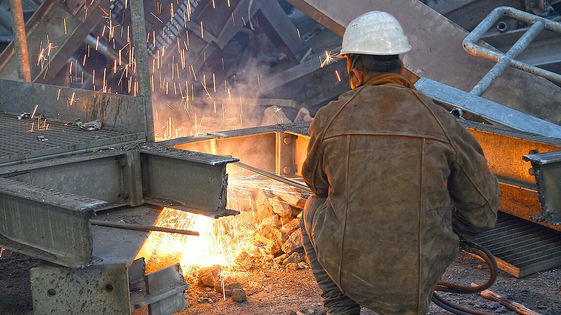 Arbeiter der an Metallteil mit Flexmaschine arbeitet
