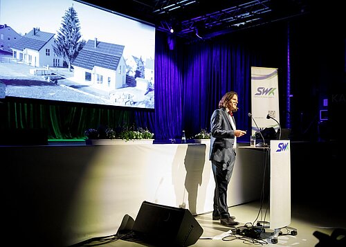 Mann spricht auf Bühne Energieforum vor Publikum Präsentation auf Leinwand