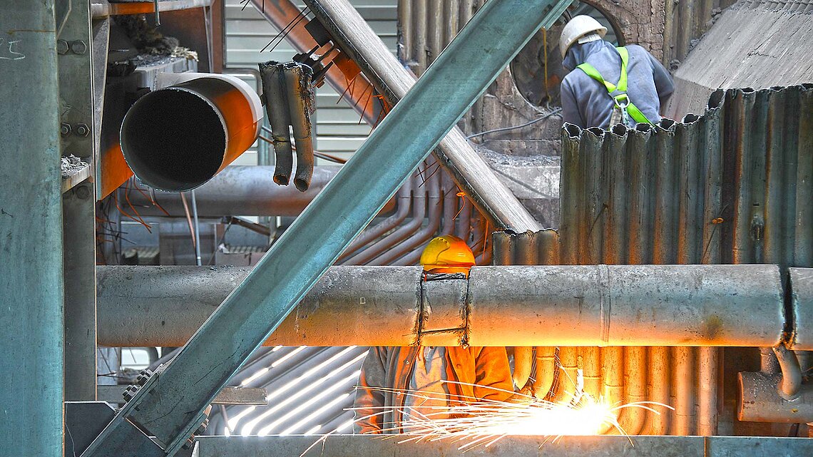 Arbeiter im Heizkraftwerk Innenbereich Flexmaschine an Metallrohr