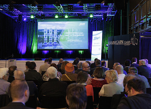 Saal mit Bühne und Publikum in Blickrichtung Leinwand.
