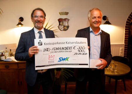 Ehemaliger SWK-Vorstand und eine weitere Person halten Scheck in der Hand für eine Spende der SWK
