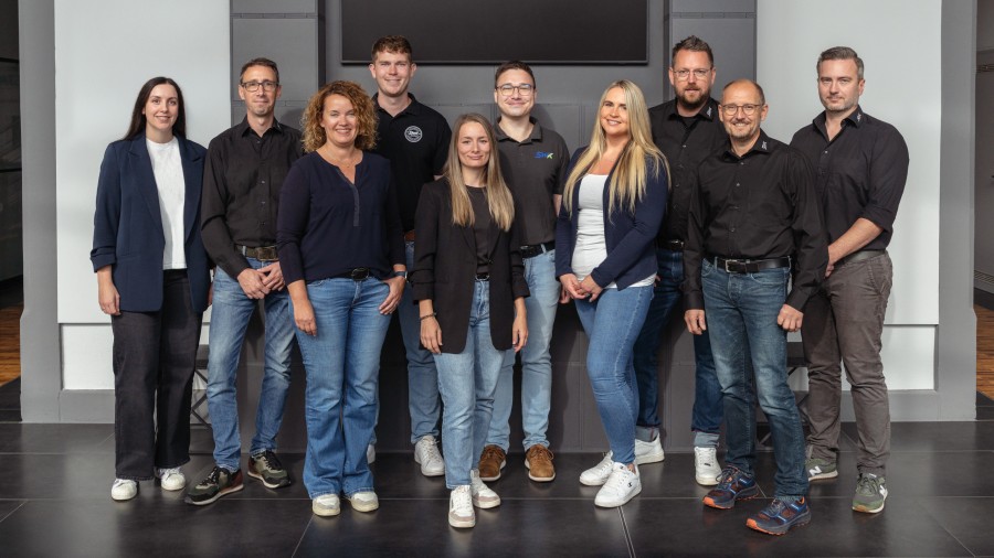 Teamfoto von zehn Mitarbeitenden der Abteilung Energiedienstleistungen vor einer grauen Bürowand.